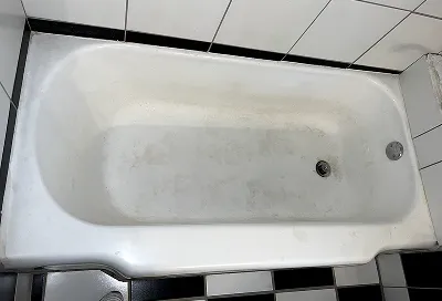 Before bathtub reglazing showing worn, stained, and damaged bathtub surface