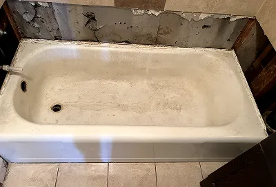 Bathtub before reglazing showing heavy stains and surface damage