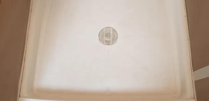 Old shower stall before refinishing with worn panels and dirty grout