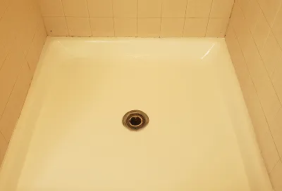 Shower stall before reglazing showing stains, discoloration, and surface wear