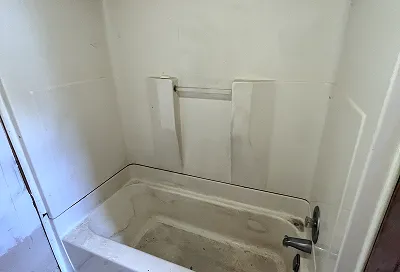 Worn shower walls before refinishing showing discoloration and buildup